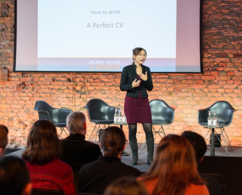 Foto von Heidi Störr als Referentin bei einem Bewerbungsseminar an der TU Berlin, 2023. Im Hintergrund sieht man eine Folie mit "How to write a perfect CV"