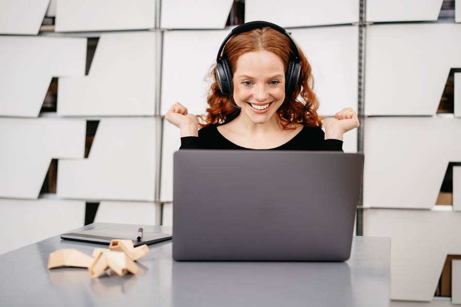 Eine Promovierende nimmt an einem Bewerbungsseminar ihrer Universität teil. Sie schaut lachend auf den Laptop auf dem das online Bewerbungstraining läuft