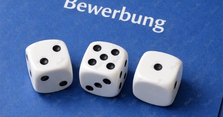 drei weiße würfel liegen auf einer bewerbung. sie symbolisieren das gefühl von zufall und glück haben müssen, vieler bewerber