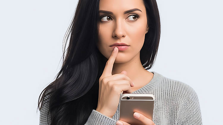 Bewerberin schaut nachdenklich auf das Handy und überlegt, ob sie das Unternehmen anrufen soll, dem sie eine Bewerbung geschickt hat